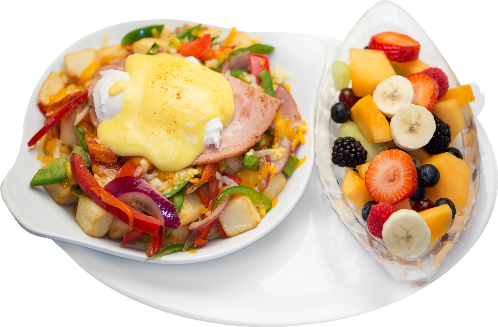Breakfast skillet topped with hollandaise, with a side of fresh fruit